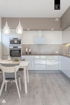 a modern kitchen with white cabinets and wood flooring is featured in this image, there are three pendant lights hanging from the ceiling