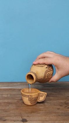 a person pouring water into a wooden bowl