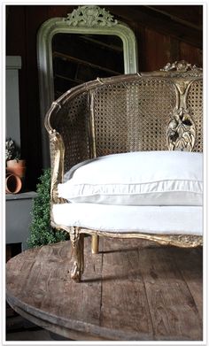 an old fashioned bed with white sheets and pillows on top of a wooden table in front of a mirror