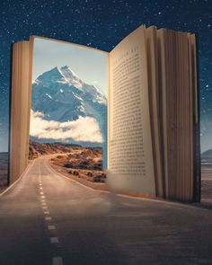 an open book sitting on the side of a road in front of a mountain range