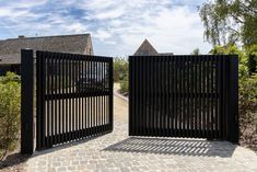 an iron gate is open on a brick walkway