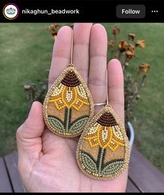 a pair of earrings with bead work on them in the palm of someone's hand