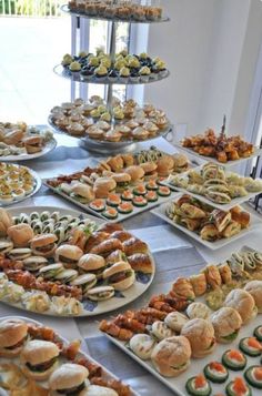 a table filled with lots of different types of sandwiches and pastries on trays