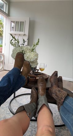 two people are sitting on the floor with their feet up and one person is wearing cowboy boots