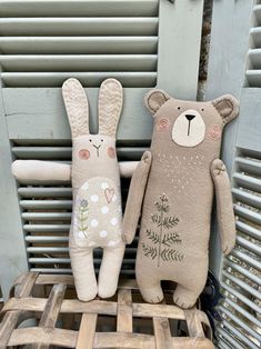 two stuffed animals sitting next to each other on top of a wooden pallet in front of a window