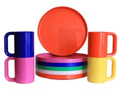 colorful cups and plates are stacked on top of each other, with one orange cup in the middle