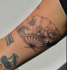 a woman with a tattoo on her arm holding an umbrella and flowers in the background