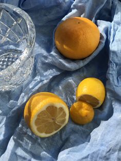 two lemons, one cut in half and the other whole on a blue cloth