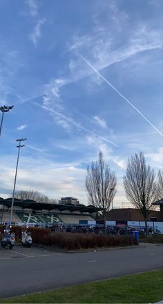 an airplane is flying high in the sky over a parking lot with cars parked on it