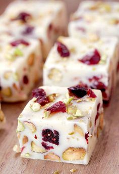 several pieces of food sitting on top of a wooden cutting board with nuts and cranberry toppings