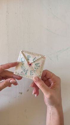 two hands holding an origami clock and pointing it at another hand with their fingers