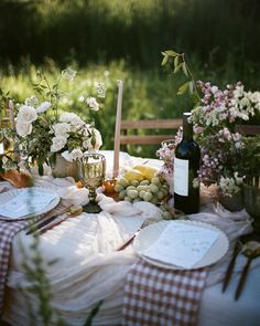 a table set with plates, wine glasses and flowers