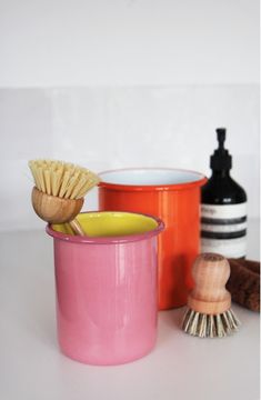 three different types of brushes and containers on a white counter top next to each other