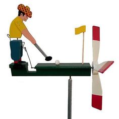 a man hitting a golf ball on top of a green table with a red and white flag