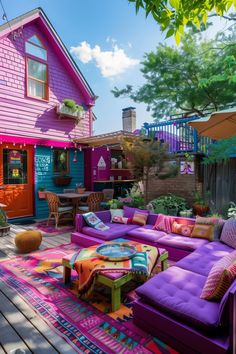 a purple couch sitting on top of a wooden floor next to a pink house with lots of windows