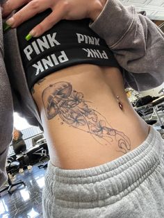 a woman with a tattoo on her stomach is looking down at the camera while wearing sweatpants