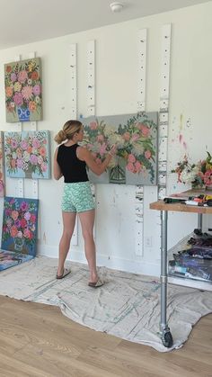 a woman standing in front of paintings on the wall