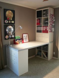 a white desk sitting under a window next to a wall mounted cd player and bookshelf