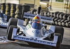 two race cars racing down a track with tires in the background