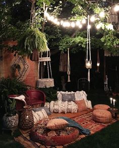 an outdoor seating area with lights strung from the ceiling and pillows on the rugs