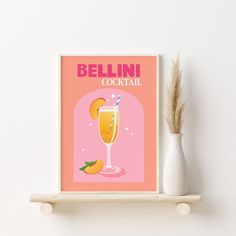 a pink poster on a shelf with a glass of orange juice and a sprig of dry grass