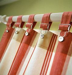 red and white striped curtains hanging from the side of a window with metal clips on them