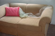 a white couch with a pink pillow on it and a plastic bag wrapped around the back