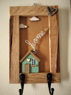 a wooden frame with a small house on it and some hooks hanging from the wall