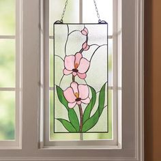 a stained glass window with pink flowers hanging from it's side and green leaves on the outside