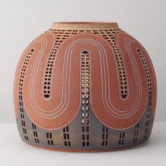 an orange and grey vase sitting on top of a table