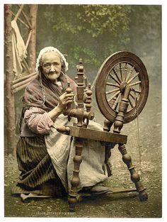 an old woman sitting in front of a spinning wheel