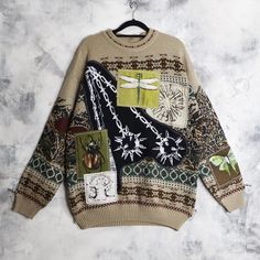 a sweater with dragonflies on it is hanging from a hanger against a wall