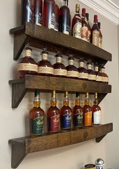 a wooden shelf filled with bottles of liquor on top of a counter next to a wall