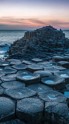 the giant stones are stacked up on top of each other by the ocean at sunset