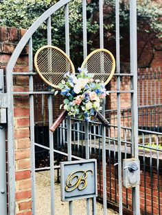 there is a tennis racket and flowers on the gated entrance to a building