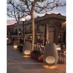 an outdoor dining area with tables, chairs and umbrellas on the patio at dusk