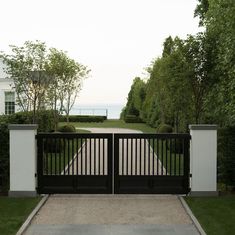 a driveway with two gates leading to a house