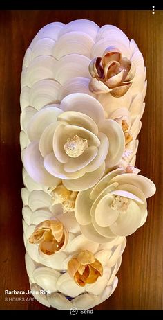 a large white vase with flowers in it on a wooden table next to a wall