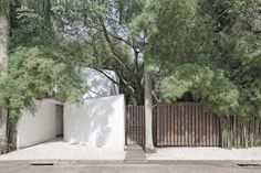 a white gate and trees in front of a house