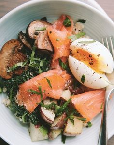 a white bowl filled with food on top of a wooden table next to a fork