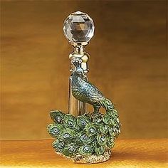 a peacock figurine sitting on top of a table next to a crystal ball