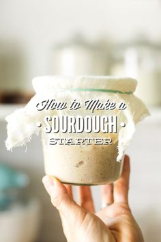 someone holding up a jar with something in it that says, how to make a sourdough starter