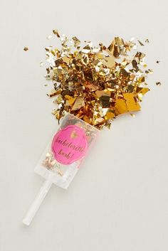 a candy filled with gold confetti and sprinkles on a white surface