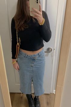 a woman taking a selfie in front of a mirror wearing black boots and jeans