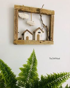 a wooden frame with some little houses on it and a fern in the foreground