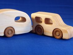 two wooden toy cars sitting side by side on a blue background, one is white and the other is brown