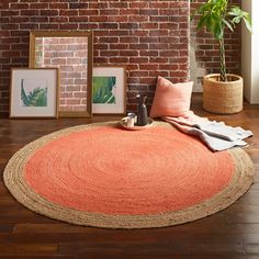 an orange rug on the floor with pictures and plants in front of a brick wall