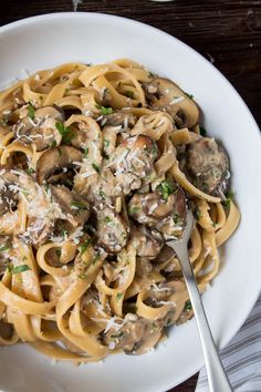 pasta with mushrooms and parmesan cheese in a white bowl on a wooden table