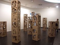 several cardboard boxes stacked on top of each other in a room with people walking around