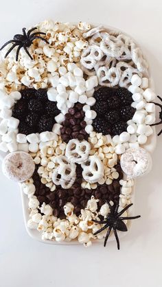 a skull made out of cereal and marshmallows on a white surface with black spider web around it